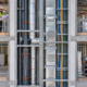 An inspector reviews plumbing, ductwork, and cable routes inside a building services shaft.