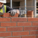 A mason and supervisor inspect a brick running bond wall with each course offset by one third of a brick length.