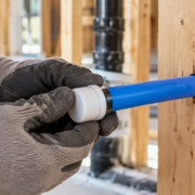 Plumber fitting an end cap onto a blue PEX water line to protect it during construction.