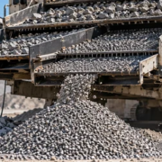 Portable vibrating screen sorts construction aggregate into separate size piles for material selection.