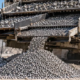 Portable vibrating screen sorts construction aggregate into separate size piles for material selection.