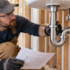 A plumber checks the curved P-trap beneath a sink before the wall is closed.