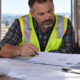 Construction estimator calculating labor burden costs beside a working crew