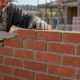 Mason laying bricks in a staggered runner bond pattern
