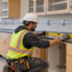 A millwork installer aligns built-in laboratory casework cabinets and checks the wall attachment before anchoring.