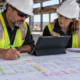 Estimators mark quantities on a commercial floor plan while comparing digital takeoff measurements on a tablet at the jobsite
