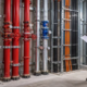 An MEP engineer and installers review organized pipe risers, valves, electrical conduits, and service clearances in a building riser room.