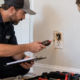 Electrician inspecting a burnt outlet with a homeowner at a repair estimate