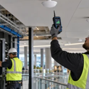 Telecom technicians install indoor antennas and organized cabling while testing building wireless coverage.