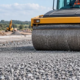 Road crew compacts graded MOT Type 1 aggregate for a stable road sub-base
