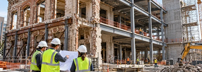 Engineers review a renovation where an existing masonry facade meets new structural framing, showing when work becomes substantial reconstruction.