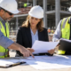 Project owner, contractor, and insurance professional check an OCIP enrollment list and policy documents at a commercial jobsite