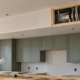 A lowered kitchen soffit encloses HVAC ductwork above cabinets, with an open section showing the hidden service.
