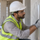 Site technician checks a prepared concrete wall with a moisture meter and straightedge before the finish is applied.