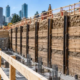 Engineer inspects timber lagging boards installed between steel soldier piles to support an excavation wall.