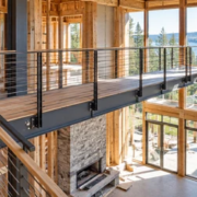 Architects and an engineer review a guarded elevated walkway crossing the double-height space of a home under construction.