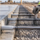 A worker checks the spacing and alignment of dowel bars crossing a concrete slab joint.