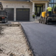A contractor mills damaged driveway pavement and lays a fresh asphalt surface while a homeowner reviews the work