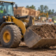 Front loader moving soil across a construction site during foundation preparation
