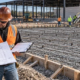 Estimators review a commercial slab plan and cost worksheet beside a reinforced concrete slab before the pour