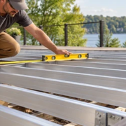 Installer measures and levels aluminum deck joists before installing decking boards.