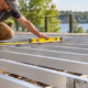 Installer measures and levels aluminum deck joists before installing decking boards.