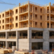 Five wood-framed residential floors rising above a two-level concrete podium