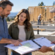 Landowner, lender, and contractor review a site plan, construction budget, and staged draw schedule beside a new home build