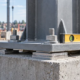 Engineer checks a steel column baseplate leveled on shim plates above a concrete pedestal.