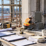 A project cost engineer records crew labor, materials, and equipment for a defined repair task at a construction site as the foreman reviews the work.