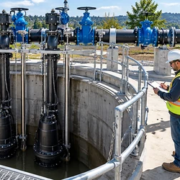 8338-feature-image A civil engineer inspects pumps, guide rails, discharge valves and controls at a concrete wastewater lift station wet well.