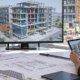 Architect and site engineer reviewing a coordinated 3D building model on a monitor and tablet