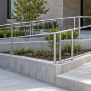 A wheelchair user follows a guarded switchback entrance ramp with level landing and continuous handrails while contractors review the route.