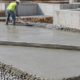Construction crew levels a plain cement concrete base before the next foundation work begins.