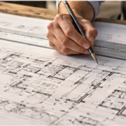 Architect drafts a measured floor plan on a drawing board with a parallel rule and scale, showing tools used to prepare precise construction drawings.