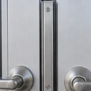 Close view of paired doors showing the narrow astragal strip at the meeting edges beside the handles and latch hardware.