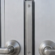 Close view of paired doors showing the narrow astragal strip at the meeting edges beside the handles and latch hardware.