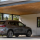 A finished carport attached to a modern home shelters a vehicle beneath a supported roof, showing how the structure connects to the house.
