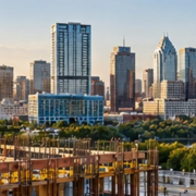 Commercial office tower rises with cranes above the Austin skyline, illustrating the city’s active commercial construction market.