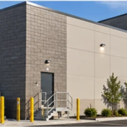Rear elevation of a modern commercial building with a service entrance, loading bays, and screened utility equipment.