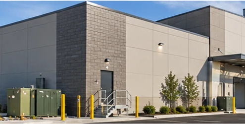 Rear elevation of a modern commercial building with a service entrance, loading bays, and screened utility equipment.