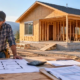 Compact starter home under construction as a homeowner and contractor review the floor plan and budget for a $150,000 build.