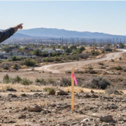 Surveyor and builder inspect an undeveloped parcel with site stakes and survey equipment before planning a new home.