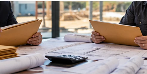 Contractors review proposal folders and construction plans during a commercial pre-bid meeting.