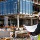 Commercial construction crew and manager coordinate steel framing, glazing, concrete and site work on a nonresidential office building.