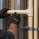 Commercial plumber installing supported cream-colored CPVC water-supply piping inside an open tenant wall.