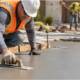 Concrete finisher smooths a level slab inside edge forms, illustrating construction flatwork.
