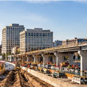 City skyline and bridge work alongside a roadway construction site, showing the range of projects in the construction industry.
