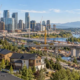 Panoramic city-development scene spanning homebuilding, commercial towers, bridge construction, and industrial facilities to show construction’s main sectors.