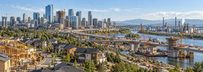 Panoramic city-development scene spanning homebuilding, commercial towers, bridge construction, and industrial facilities to show construction’s main sectors.